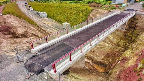 Wirtschaftswegüberführung "Hasselhof" (BW 5) nach Fertigstellung im Juli 2020. Als Restarbeiten fehlen noch die Pflasterarbeiten unterm Bauwerk und Straßenanschlüsse. Landschaftsaufnahme mit Arbeiten an der Wirtschaftswegüberführung im Vordergrund einer grünen Landschaft