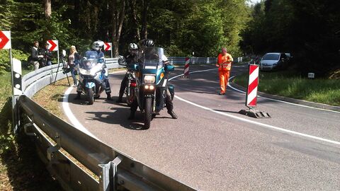 Motorisierte Zweiradfahrerinnen und -fahrer begutachten eine Straßenkurve. 