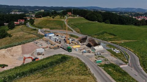 Eine Staßenbaustelle mit Kran und Bagger, aufgenommen von einer Drohne.