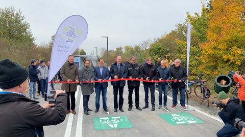 Im Oktober ist ein weiterer Abschnitt des ersten Hessischen Radschnellweges zwischen Frankfurt und Darmstadt fertiggestellt worden. Der Radschnellweg hat Fördermittel seitens der Verkehrsinfrastrukturförderung bei Hessen Mobil erhalten. Mehrere Personen mit Scheren in den Händen sind bereit das symbolische Band zur Freigabe zu durchschneiden.