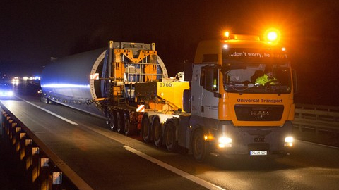 Schwertransport nachts mit eingeschalteter Beleuchtung auf einer Straße