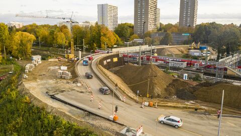 Eine Drohnenaufnahme, die eine Brückenbaustelle über eine S-Bahnlinie zeigt. Im Hintergrund sind Hochhäuser zu sehen.