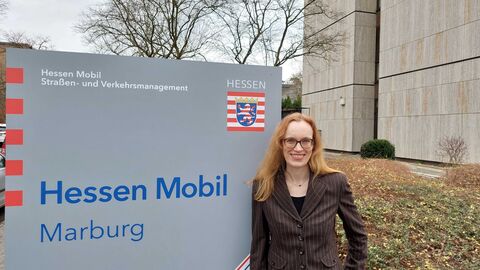 Sonja Lecher - Regionalbüro Westhessen Sonja Lecher, Sachgebietsleiterin der Region Westhessen steht vor einem Hessen Mobil Schild vor dem Standort in Marburg.