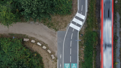 Drohnenbild eines Radwegschnellweges mit Piktogrammen.