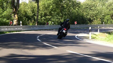 Ein Motorradfahrer befährt auf einer Landstraße ene Kurve. 
