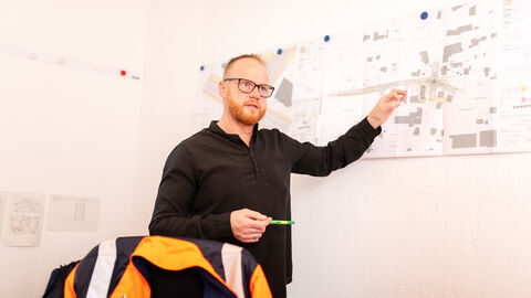 Mitarbeiter von Hessen Mobil erklärt einen an der Wand hängenden Plan