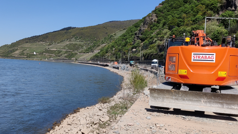B 42 - Baustellenbereich zwischen Lorch und Rüdesheim-Assmannshausen  Im Baustellenbereich zwischen Lorch und Rüdesheim-Assmannshausen steht ein orangefarbener Bagger.