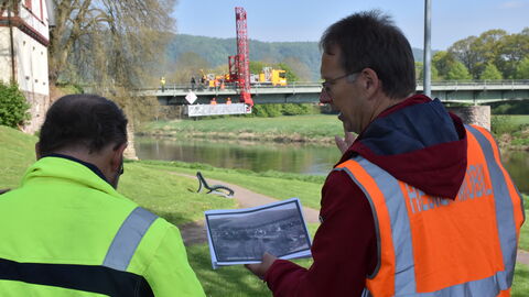 Bauwerksprüfung Gieselwerder 6 Die Bauwerksprüfer von Hessen Mobil betrachten ein altes Bild der denkmalgeschützten Brücke