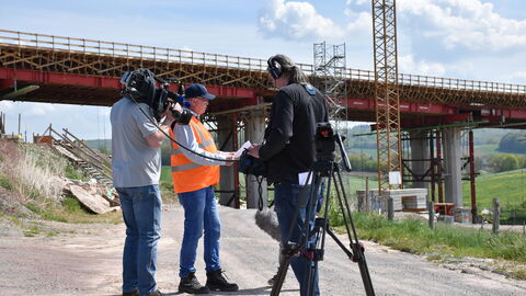 Pressetermin Ortsumgehung Bad Karlshafen 1 Ein Brückenexperte von Hessen Mobil im Interview mit einem Fernsehteam an der Ortsumgehung Bad Karlshafen