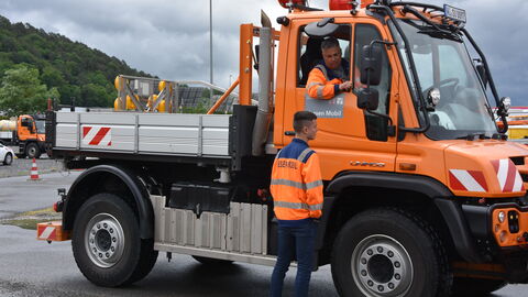Trainingstag Schneepflugmeisterschaft 19 Ein Straßenmeister gibt dem Fahrer eines Unimogs Tipps durch das geöffnetet Fahrerfenster