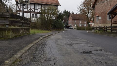Eine Fahrbag´hn mit zahlreichen Asphaltflicken ein Fachwerkhaus im Hintergrund