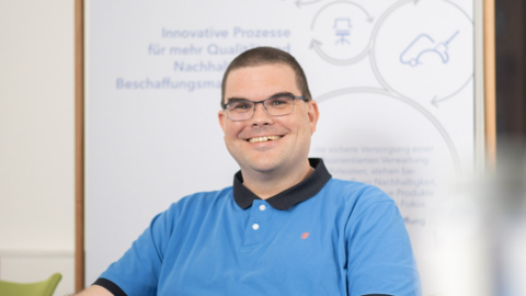 Andreas Weigmann - Sachgebietsleiter Einkauf Herr Andreas Weigmann vom Sachgebiet Einkauf sitzt auf einem Stuhl und blickt lächelnd in die Kamera.