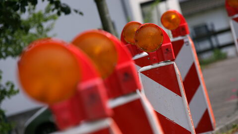 Warnbaken Mehrere rot-weiße Warnbaken hintereinander aufgestellt - der Vordergrund unscharf, der Hintergrund scharf