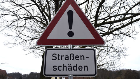 Warnschild Straßenschäden rot-weißes Dreiecks-Warnschild mit der Aufschrift Straßenschäden