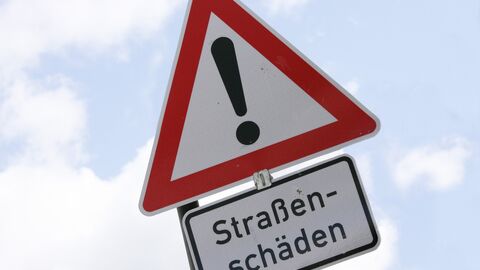 Straßenschäden In Großansicht ist ein Verkehrzeichen mit einem Ausrufezeichen zu sehen. Darunter befindet sich ein Schriftzusatz mit dem Text "Straßenschäden"."