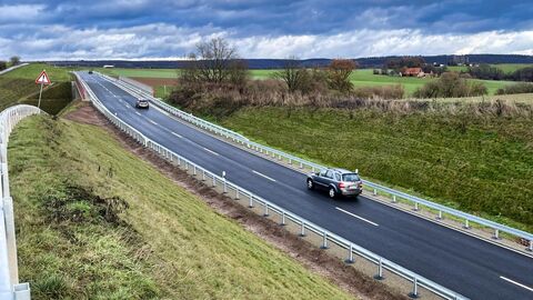 Bauwerk 2 - Brücke über Höllebach und Wirtschaftsweg 2 Autos fahren auf einer Straße. Neben der Straße sind Grünflächen.