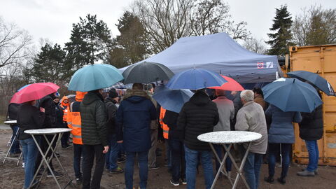 Spatenstich Radweg Okarben-Niederwöllstadt 4 Einige Gäste stehen mit Regenschirmen vor dem Pavillion