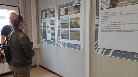 Besucher/innen der Ausstellung vor einem Plakat