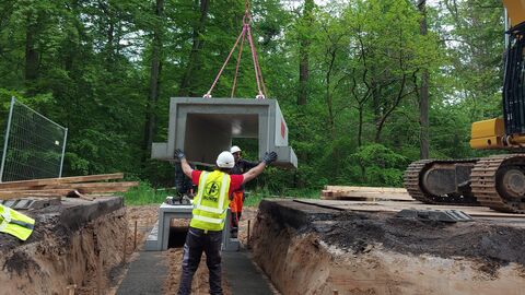 Einhub Amphibienschutztunnel im Zuge des Radwegsneubaus in Viernheim An einem Kran werden Fertigbetonteile eingehoben - ein Bauarbeiter unterstützt
