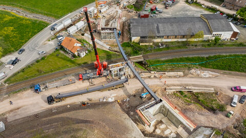 Ein Drohnenbild zeigt den Einbau von sehr langen Brückenfertigteilen aus Stahl an einer Brücke.