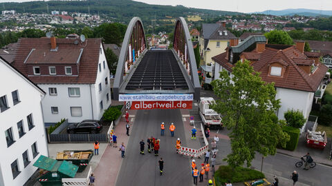 Transport der Brücke in Niedernhausen 6 Das Brückenteil aus Stahl rollt langsam zwischen den Häusern hindurch