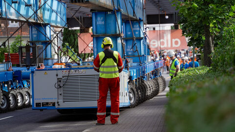 Das Brückenteil aus Stahl auf dem Schwertransport mit vielen kleinen Rollen