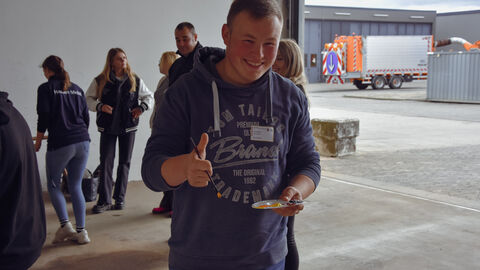 Azubitag 2023 auf der SM Alten-Buseck -22 Ein Azubi grinst in die Kamera - er hat einen Farbtopf in der Hand