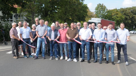 Zahlreiche Beteiligte der Baumaßnahme durchschneiden das symbolische Band