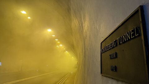 Rauchsimulation Schürzebergtunnel 4 Rauch wabert durch den Tunnel, der gelb beleuchtet ist. Das Notausgangsschild ist rechts zu sehen