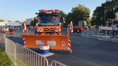 Deutsche Meisterschaft im Schneepflugfahren 2023 - 3 Orangefarbener Unimog mit Schneepflug im Geschicklichkeitsparcours