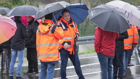 Mehrere Menschen stehen mit Schirmen im gespräch beieinander