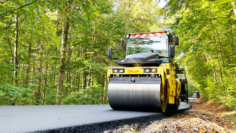 Eine Walze fährt über die frisch asphaltierte Landesstraße