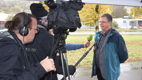 Prof. Linke gibt ein Interview umringt von Kameras und Mikrofonen