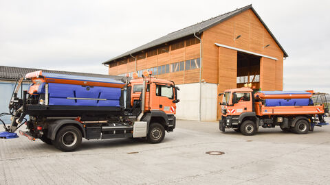 Pressetermin Auftakt Winterdienstsaison 2023-6 Zwei orangefarbene Hessen Mobil Streufahrzeuge stehen vor der Salzhalle