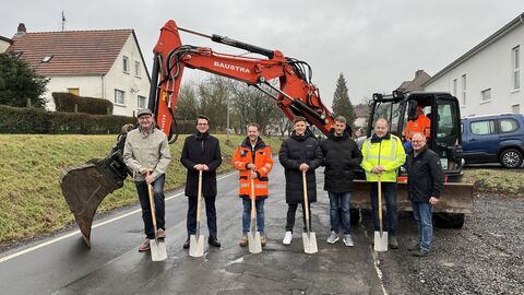 Spatenstich an der K37 OD Reiskirchen-Saasen mit sieben Personen - ein Bagger im Hintergrund