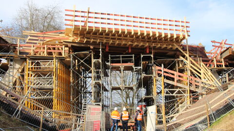 Drei Hessen Mobil-Ingenieure stehen vor einer Brückenbaustelle