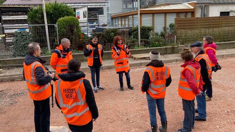 Eine Gruppe in orangenen Warnwesten läuft über die Baustelle