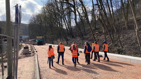 Eine Gruppe in orangenen Warnwesten läuft über die Baustelle