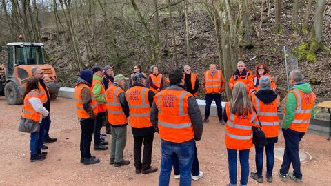 Eine Gruppe in orangenen Warnwesten läuft über die Baustelle