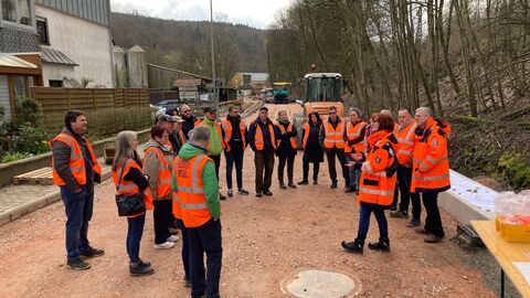 Eine Gruppe in orangenen Warnwesten läuft über die Baustelle
