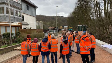 Eine Gruppe in orangenen Warnwesten läuft über die Baustelle