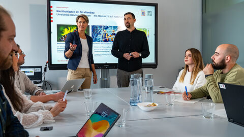 Frau und Mann zeigen vor Publikum eine Powerpoint